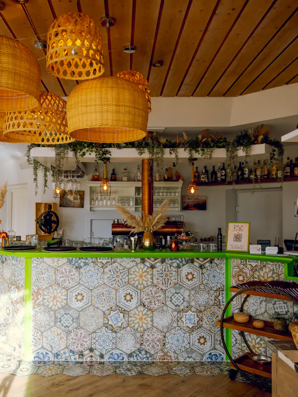 Bar mit Mosaikfliesen und Rattanlampen in der Taverna Athos