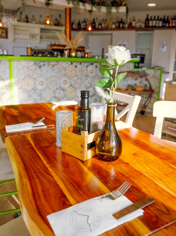 Gedeckter Holztisch mit Olivenöl und Blume im Gastraum